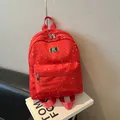Mochila roja de moda con estrellas y placa de metal dorada sobre libro de diseño - Rojo