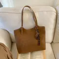 Detalle de bolso tote de cuero marrón con hebilla metálica y colgante de ábaco - Con Colgante / Marrón