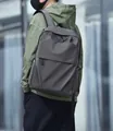 Minimalist grey nylon backpack for men shown on model against an urban backdrop - Gray