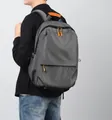 Grauer Reiserucksack mit großen Kapazität und orangen Details auf einem männlichen Model - Grau