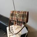 Detail view of checkered tweed crossbody bag with golden S-buckle and metal tassel - Brown