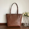 Detalle de la textura de cuero trenzado marrón oscuro en un bolso tote grande - Marrón