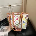 Dettaglio di motivi monogramma colorati e manici in pelle su una grande borsa tote bianca - Bianco