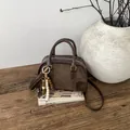Detailed macro of vintage brown leather bag featuring wood bead pendant and golden hardware - With Pendant / Brown