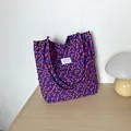 Lilafarbene geblümte Shopper-Tasche aus strukturiertem Popcorngewebe auf Holztisch - Lila