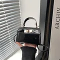 Detail of black patent leather mini bag with gold twist lock and metallic ring handle - Black