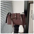 Detail of dark brown suede handbag with leather straps and silver buckle in natural light - Brown