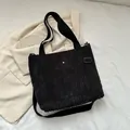 Bolso tote minimalista en pana negra con correa ajustable y detalle de hebilla metálica - Negro