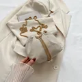 Beigefarbene Beuteltasche mit goldener Kette und Perlenverzierung auf Webstruktur - Beige
