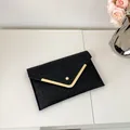 Elegant black envelope clutch bag with crocodile texture and golden V-shaped trim - Black