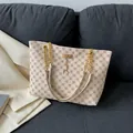 Beigefarbene Shopper-Tasche mit Kleeblatt-Muster und goldener Kette auf Sofa - Weiß