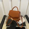 Brown vintage handbag with crocodile texture and gold chain strap on black chair - Brown