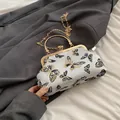 Bolso de tela blanca con bordado de mariposa negro y dorado y asa de metal circular - Blanco
