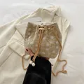 Détail du sac seau en paille avec broderie florale, chaîne dorée et perles - Kaki
