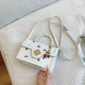 White mini square handbag with red cherry print, braided handle, and floral clasp lock - Off-white