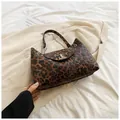 Detailed view of leopard print crescent bag featuring a metallic T-shaped buckle and chain strap - Brown