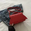 Rode vierkante crossbodytas in vleermuisvorm gepresenteerd op een spijkerjasje - Rood