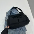 Bolso tote de lona negra minimalista con diseño multibolsillo y correa ajustable - Negro