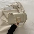 Chic cream-colored shoulder bag with a gold U-shaped clasp and knotted strap detail - White