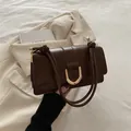 Chic dark brown leather shoulder bag featuring a vintage gold horseshoe buckle and knot detail - Brown