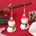 Detailed close-up of Christmas snowman earrings with red hats and green scarves on wood - Snowman with Scarf (EH5957)