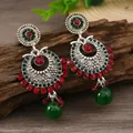 Primer plano de pendientes boho plateados con pedrería roja y verde sobre madera - Estilo Plata Antigua Rojo (weh5903)
