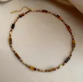 Macro detail of tiger eye stone beads and gold lobster clasp on beaded necklace - Maillard Beaded Necklace