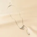 Detail of silver Y-shaped tassel necklace with interlocking rings on silk fabric - Double Rings / Silver