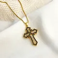 Detailed close-up of a gold cross necklace with pavé-set white and black zircon stones - Gold