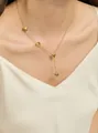 Detail view of 18K gold heart tassel necklace on model wearing V-neck top - Golden Heart
