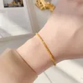 Elegante collana dorata con trama intrecciata indossata da una modella in stile francese - Bracciale scintillante SL5110J dorato