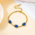 Detailed view of a gold snake chain necklace with three oval blue emerald-cut gemstones - Blue Bracelet