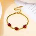 Close-up of golden blade chain necklace featuring three oval red emerald gemstones - Dark Red Bracelet