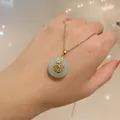 Detail of a vintage gold necklace featuring a round green jade pendant with Fu character - Green