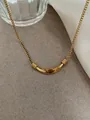 Macro shot of gold curved bar necklace with tiger eye stone on a textured grey surface - Tiger Eye Titanium Steel Necklace