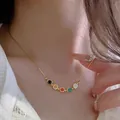 Nahaufnahme einer goldenen Halskette mit fünf bunten Emaille-Smiley-Anhängern am Modell - 411 Bunte Smiley-Gesicht-Halskette (Gold)