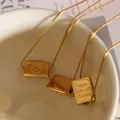 Three gold triangle smile necklaces with engraved rectangular pendants on white ceramic - Gold