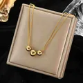 Detail of three polished gold beads on a delicate chain against a black velvet background - Gold Multi-beaded Style