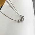Macro shot of minimalist triple bead pendant on a layered silver tone metal chain - Silver Multilayer Bead Style