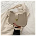 Détail du sac demi-lune beige élégant avec fermoir en métal doré et surpiqûres raffinées - Blanc