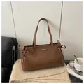 Detalle de un bolso tote de cuero marrón con lazo lateral y logotipo de moda grabado - Sin colgante / Marrón