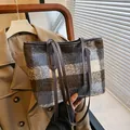 Blauw en bruin geruite wollen tote tas met leren hengsels op een beige jas getoond - Blauw
