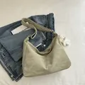 Pale green textured leather tote bag with white plush bear charm on denim jeans background - With Pendant / Green