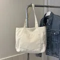 Beigefarbene Cord-Einkaufstasche mit Vordertasche und quadratischem Etikett am Bügel - Gebrochenes Weiß