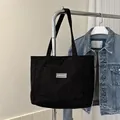 Schwarze Cord-Schultertasche mit praktischer Fronttasche und gewebtem Etikett - Schwarz