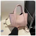 Detalle de bolso bandolera de ecopiel rosa con textura vintage sobre una silla blanca - Rosa