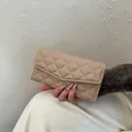 Portefeuille long matelassé beige élégant avec rabat en V tenu par un modèle - Khaki