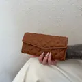 Portefeuille long marron matelassé à losanges style enveloppe tenu sur fond neutre - Marron