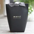 Elegant black trapezoid gift bag with a grey satin bow and gold foil merci beaucoup text - 8x5.5x16.5cm / Black