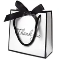 Minimalist white gift bag with black trim, satin bow, and Thank You lettering - Handheld White With Black Border